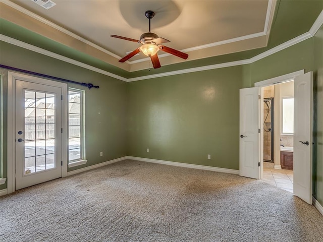 spare room with light carpet, baseboards, a raised ceiling, ceiling fan, and crown molding