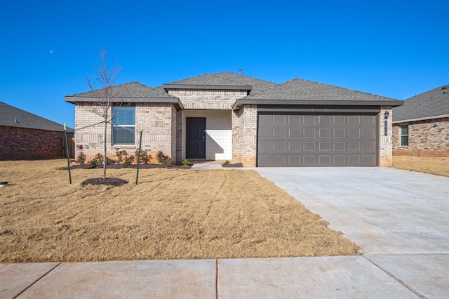 view of front of property featuring a garage, brick siding, a shingled roof, concrete driveway, and a front yard