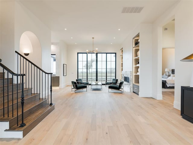 entryway with light wood-type flooring, a notable chandelier, and a fireplace