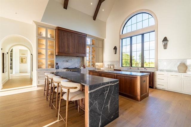 20945 Alba Ct, Edmond, OK 73012 - kitchen featuring a center island, light wood finished floors, high vaulted ceiling, glass insert cabinets, and beamed ceiling