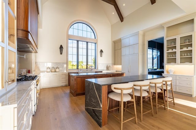 20945 Alba Ct, Edmond, OK 73012 - kitchen with gas range, a center island, high vaulted ceiling, light wood-style flooring, and beam ceiling