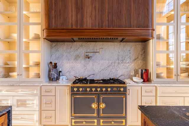 20945 Alba Ct, Edmond, OK 73012 - kitchen featuring range with two ovens, premium range hood, backsplash, dark stone countertops, and white cabinetry