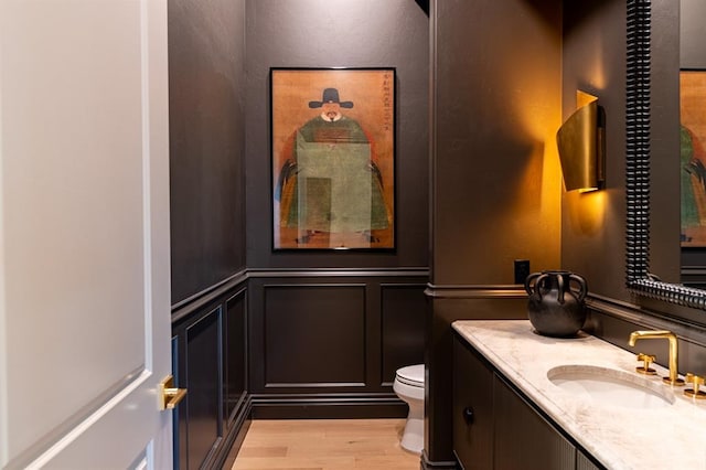 20945 Alba Ct, Edmond, OK 73012 - bathroom with a decorative wall, vanity, toilet, wood finished floors, and wainscoting