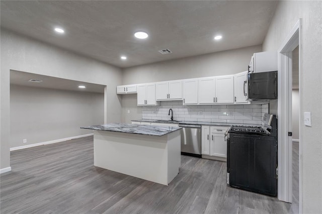 kitchen with appliances with stainless steel finishes, dark wood-type flooring, a center island, sink, and white cabinetry