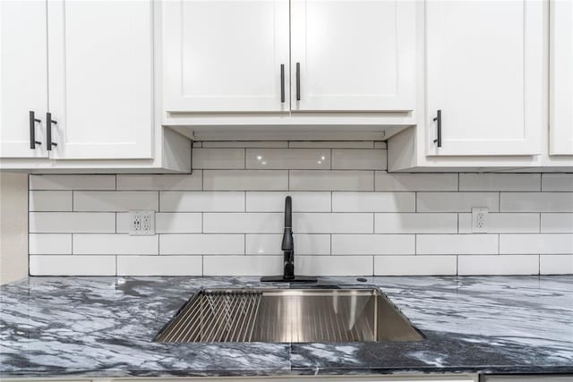 room details featuring white cabinetry, sink, dark stone counters, and tasteful backsplash