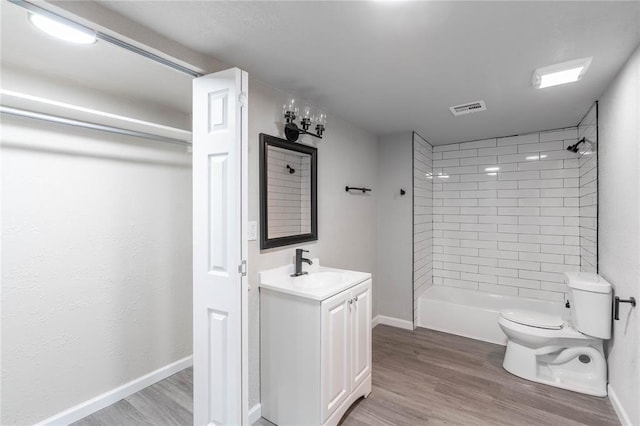 bathroom featuring toilet, wood-type flooring, vanity, and a tile shower