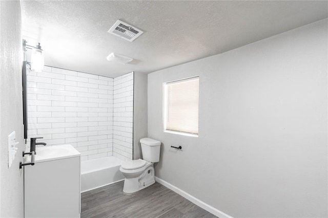 full bathroom with wood-type flooring, vanity, a textured ceiling, tiled shower / bath, and toilet