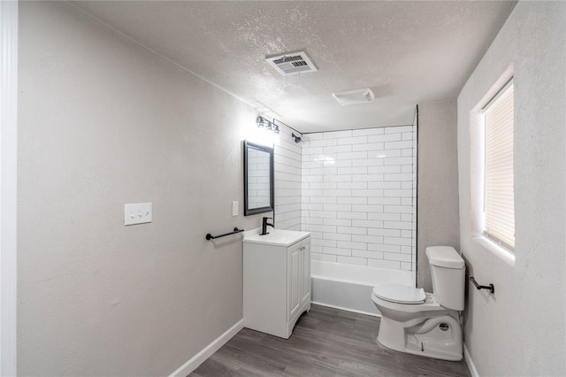 full bathroom featuring toilet, tiled shower / bath, a textured ceiling, vanity, and hardwood / wood-style floors