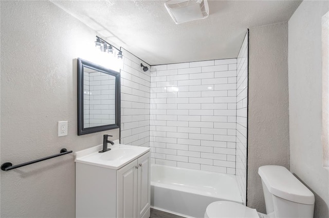 full bathroom with a textured ceiling, vanity, toilet, and tiled shower / bath