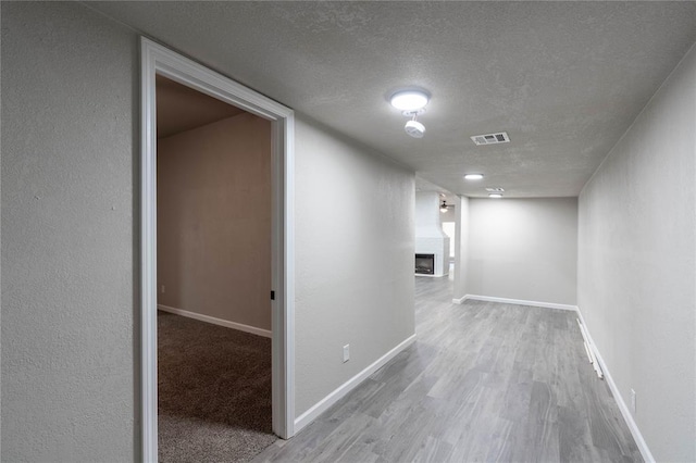 hall with light hardwood / wood-style floors and a textured ceiling