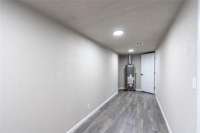 hallway with light hardwood / wood-style floors and water heater