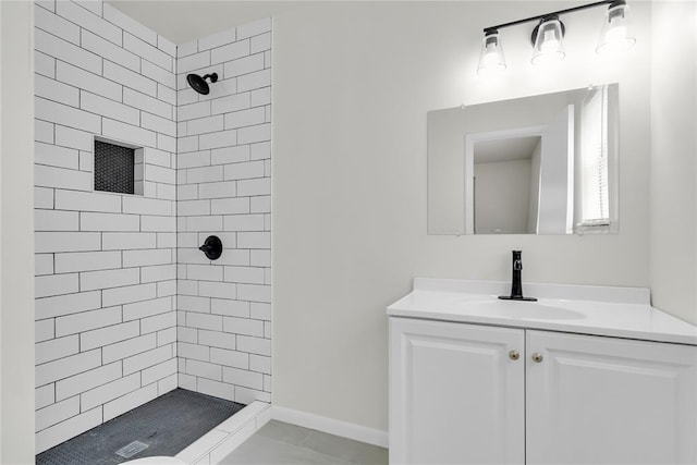 bathroom featuring baseboards, a tile shower, and vanity