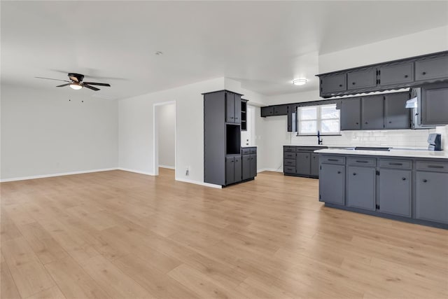 kitchen featuring light wood-type flooring, ceiling fan, backsplash, and baseboards