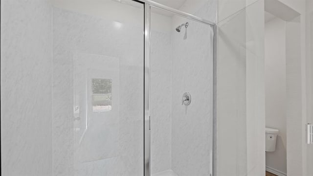 bathroom featuring toilet and a shower with shower door