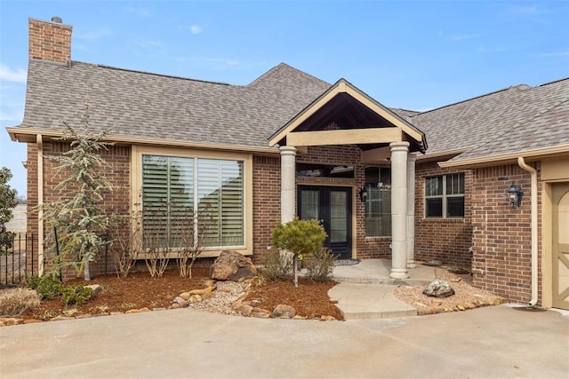 view of front of property featuring a garage, a shingled roof, a chimney, and brick siding