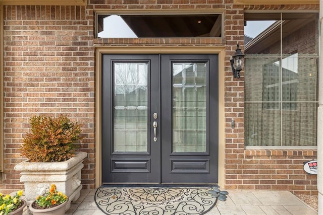 entrance to property featuring french doors and brick siding