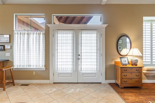 entryway with baseboards, a wealth of natural light, and tile patterned floors