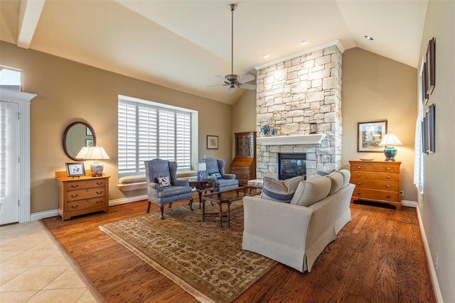 living area featuring vaulted ceiling, ceiling fan, a fireplace, and wood finished floors