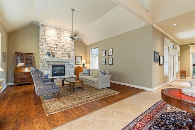 living area featuring tile patterned flooring, vaulted ceiling, a stone fireplace, and ceiling fan