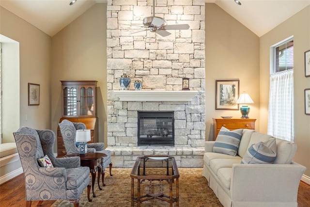 interior space featuring baseboards, a fireplace, a ceiling fan, and wood finished floors