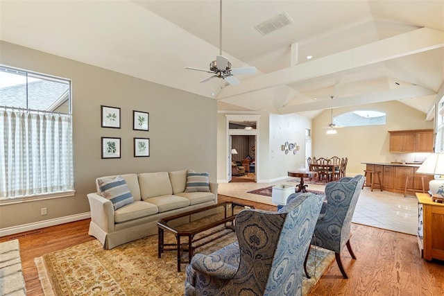 living area featuring vaulted ceiling, a ceiling fan, visible vents, and a healthy amount of sunlight