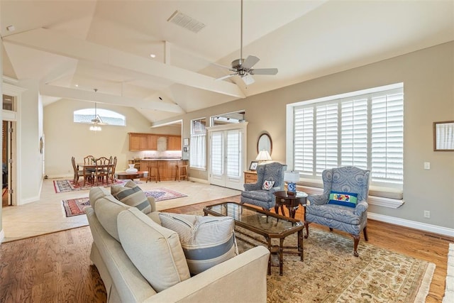 living area featuring vaulted ceiling, a wealth of natural light, visible vents, and light wood-style floors