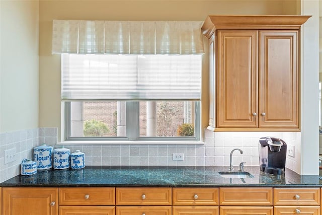 kitchen featuring tasteful backsplash, a sink, and dark stone countertops