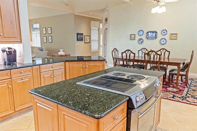 kitchen featuring a center island, stainless steel electric stove, a ceiling fan, light tile patterned flooring, and dark stone counters