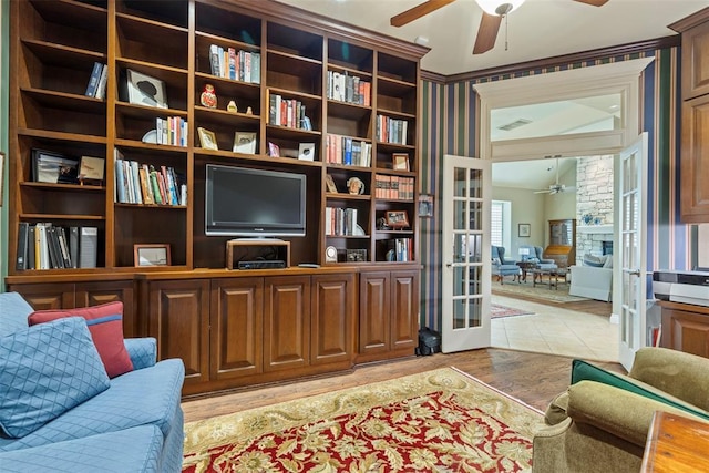 sitting room with ceiling fan, a fireplace, wood finished floors, and french doors