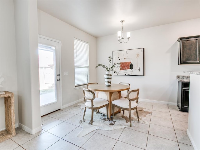 dining area featuring an inviting chandelier, light tile patterned flooring, and baseboards