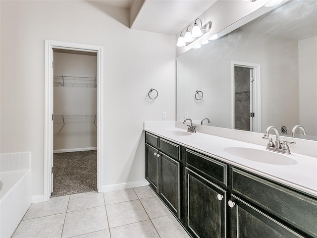 bathroom featuring tile patterned flooring, double vanity, a walk in closet, and a sink