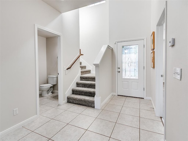 foyer entrance with stairs, light tile patterned flooring, and baseboards