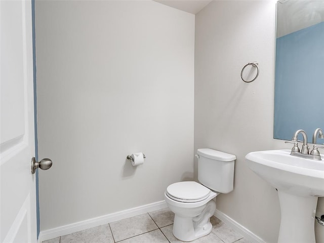 bathroom with tile patterned floors, toilet, baseboards, and a sink