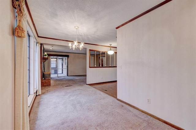 empty room featuring baseboards, ornamental molding, carpet, a textured ceiling, and a notable chandelier