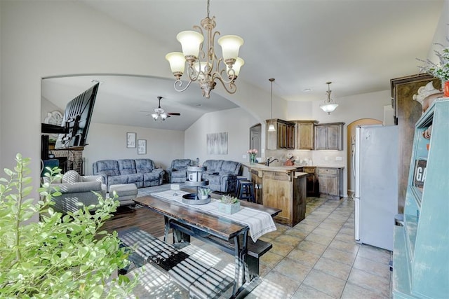 living room featuring vaulted ceiling, light tile patterned floors, ceiling fan, a fireplace, and sink