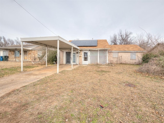 view of front of house with solar panels, a front yard, and a carport