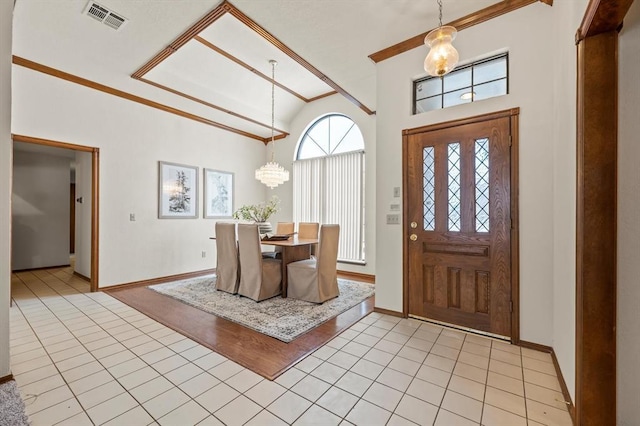 entrance foyer with light tile patterned floors, an inviting chandelier, visible vents, and crown molding