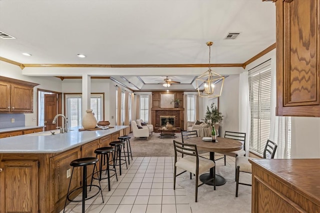 kitchen featuring decorative light fixtures, light countertops, visible vents, open floor plan, and a brick fireplace