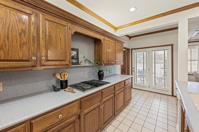 kitchen with brown cabinetry, ornamental molding, black electric cooktop, light countertops, and light tile patterned flooring