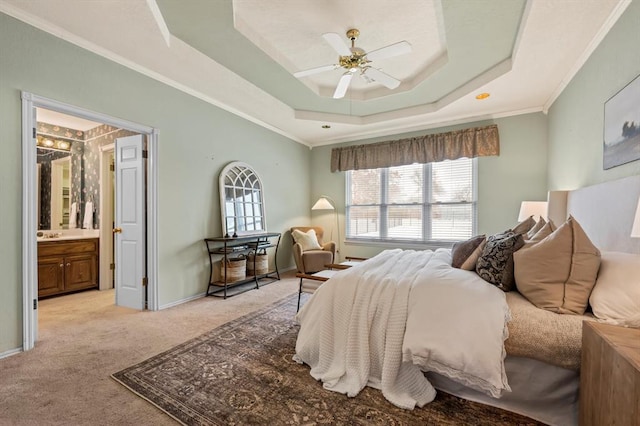 bedroom with a raised ceiling, light colored carpet, ensuite bathroom, ornamental molding, and baseboards