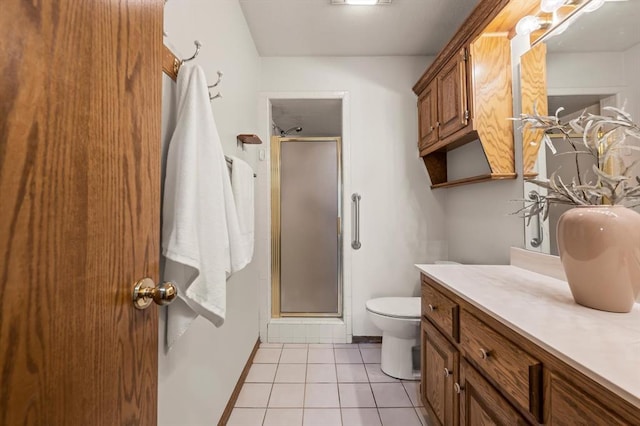 bathroom featuring toilet, a stall shower, vanity, and tile patterned floors