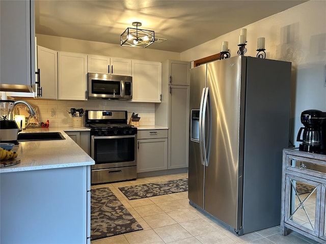 kitchen with sink, tasteful backsplash, gray cabinetry, and stainless steel appliances