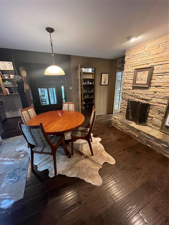 dining area with dark wood-type flooring and a stone fireplace