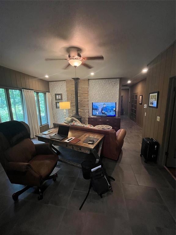 living room featuring a wood stove and ceiling fan