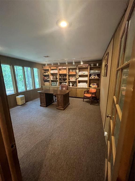 office area with track lighting, built in desk, and dark colored carpet