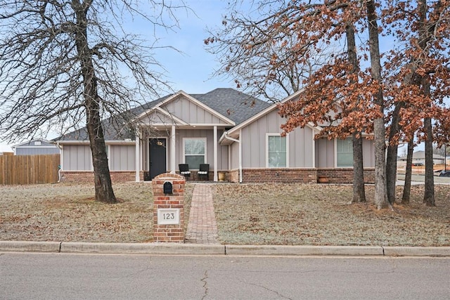 craftsman-style house with roof with shingles, fence, board and batten siding, and brick siding