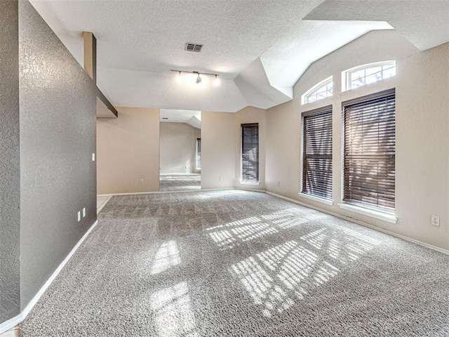 carpeted spare room featuring vaulted ceiling and a textured ceiling