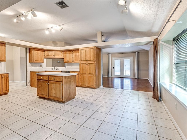 kitchen with a textured ceiling, sink, a center island, and light tile patterned floors