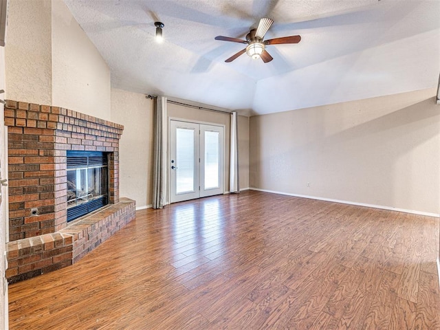 unfurnished living room with a fireplace, vaulted ceiling, ceiling fan, a textured ceiling, and hardwood / wood-style floors