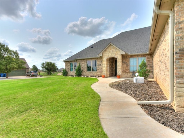 view of front of property with brick siding, roof with shingles, and a front yard